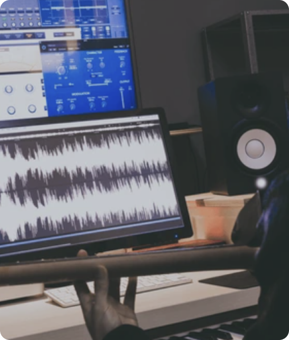 A musician holding a guitar in a modern music production studio, with a digital audio workstation on the screen displaying waveforms and various audio processing plugins.
